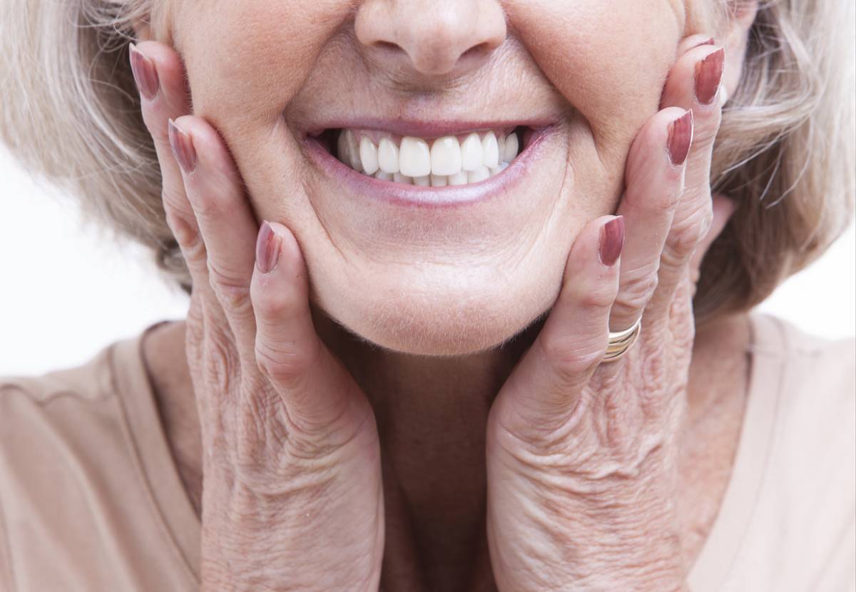 Woman smiling because she knows how to avoid unwanted side effects of dentures.
