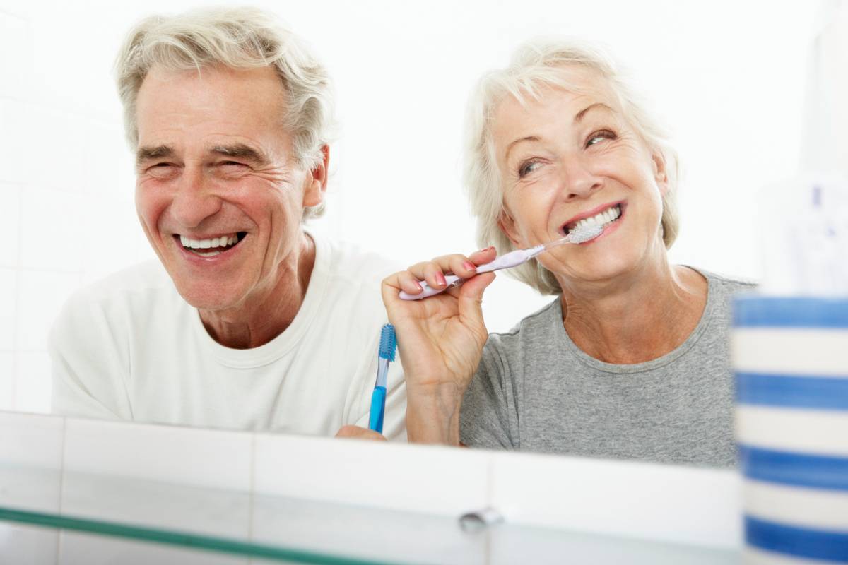 Couple brushing teeth to ensure implants do not wear down